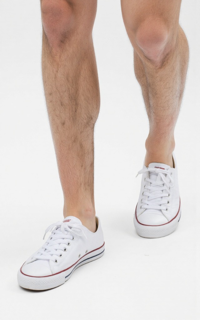A male model wearing Tennis shoes, against a white background, with a close   up of the feet